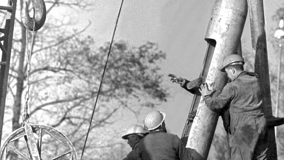 Helfer stehen am 7.11.1963 während der dramatischsten Rettungsaktion in der Geschichte des deutschen Bergbaus an der Bohrstelle in Lengede neben der so genannten "Dahlbusch-Bombe", mit der später die im Bergwerk Eingeschlossenen ans Tageslicht gezogen werden. © dpa - Bildfunk Foto: dpa