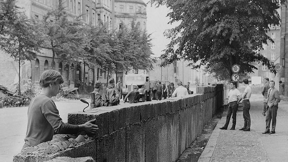 Von bewaffneten Volkspolizisten bewachte Bauarbeiter errichten die Mauer zwischen Potsdamer Platz und Lindenstraße. © picture-alliance / AKG Foto: AKG Berlin