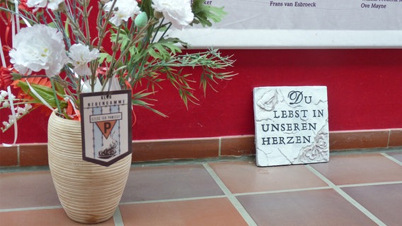 Eine Vase mit Blumen und ein Erinnrungs-Kachel  im Haus des Gedenkens in Hamburg-Neuengamme © NDR Foto: Irene Altenmüller