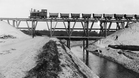 Eine Eisenbahn fährt über eine Transportbrücke beim Bau des Nord-Ostsee-Kanals © Landesarchiv Schleswig-Holstein LASH 51_III_59, Abt. 2003.8 Nr. 904 