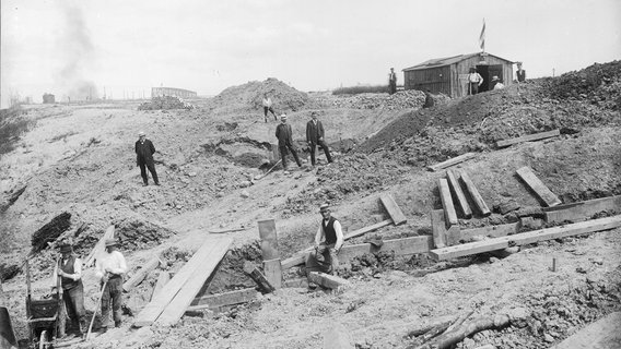Arbeiter legen Sicherungen in der Südrampe ein, um eine Rutschung beim Bau der Hochbrücke Holtenau zu verhindern. Arbeiter legen Sicherungen in der Südrampe ein, um eine Rutschung beim Bau der Hochbrücke Holtenau zu verhindern. © Landesarchiv Schleswig-Holstein LASH 53_V_570, Abt. 2003.8 Nr. 826