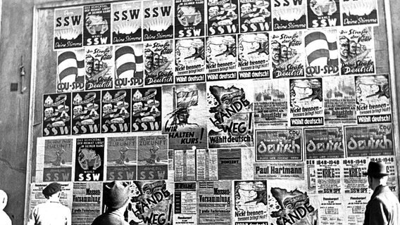 Eine Plakatwand mit Wahlplakaten des deutschen Blocks (CDU und SPD) und des Südschleswigschen Wählerverbands (SSW) für die Gemeindewahlen in Schleswig-Holstein, aufgenommen am 24.10.1948 in Flensburg. © picture alliance / dpa-Report 