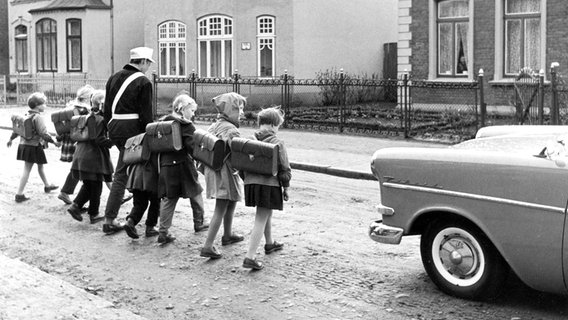 Ein Schülerlotse hilft Erstklässern 1959 in Norddeutschland auf ihrem Schulweg über die Straße. Ein Schülerlotse hilft Erstklässern 1959 in Norddeutschland auf ihrem Schulweg über die Straße. © picture alliance Foto: Charlotte Fischer