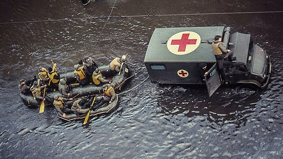Blick auf ein Rettungsfahrzeug und Schlauchboote in der überfluteten Veringstraße in Hamburg-Wilhelmsburg nach der Sturmflut 1962. © NDR Foto: Karl-Heinz Pump