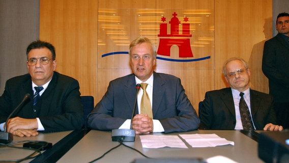 Hamburgs Bürgermeister Ole von Beust (CDU) gibt am 9.12.2003 eine Pressekonferenz in Hamburg, neben ihm sitzen der Bundesvorsitzende der Partei Rechtsstaatlicher Offensive (Schill-Partei) und Zweite Bürgermeister der Hansestadt, Mario Mettbach (l.), und der neue Bildungssenator Reinhard Soltau (FDP, r.). © picture-alliance / dpa Foto: Maurizio Gambarini