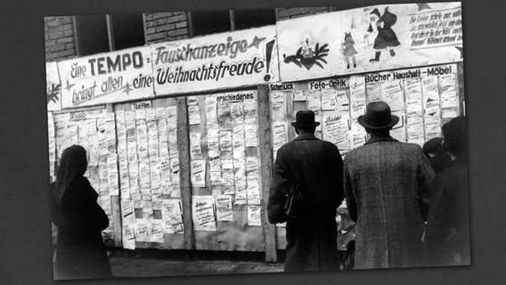 Passanten lesen in einer deutschen Stadt in der Vorweihnachtszeit 1946 Tauschanzeigen auf einer Stellwand. © dpa - Bildarchiv 