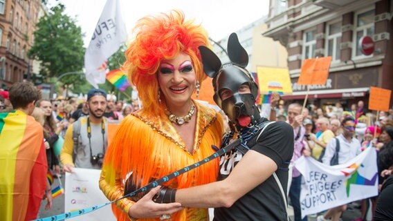 Die Dragqueen Olivia Jones (l) posiert am 05.08.2017 während der Parade zum Christopher Street Day in Hamburg mit einem maskierten Fan. © dpa Foto: Daniel Reinhardt