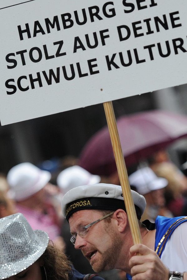 Ein Mann bei der Christopher Street Day Parade in Hamburg 2012 mit einem Schild, auf dem steht: "Hamburg sei stolz auf deine schwule Kultur!" © dpa Foto: Angelika Warmuth