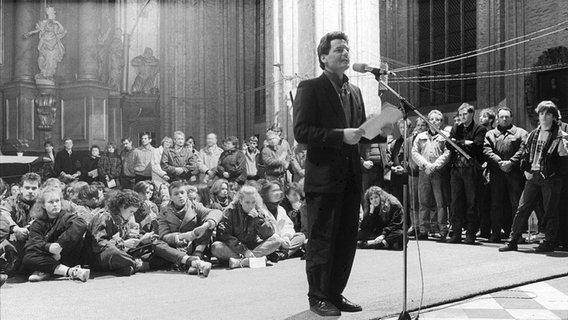 Joachim Gauck  steht im Herbst 1989 in der Marienkirche in Rostock vor einem Mikrofon und hält eine Rede. © picture alliance / dpa Foto: Siegfried Wittenburg