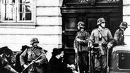 Polizisten und Zivilisten vor dem Gestapo-Hauptquartier, undatierte Aufnahme aus dem Zweiten Weltkrieg. © picture alliance/United Archives | 91050/United_Archives/TopFoto 