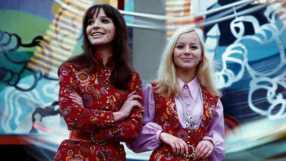 Mode in der DDR 1970: Zwei Models präsentieren einen Hosenanzug mit Tunika und Minirock mit Weste und Bluse der VVB-Konfektion. © picture-alliance/akg-images Foto: Guenter Rubitzsch