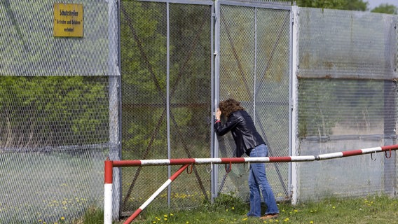 Eine Frau schaut durch den Metallgitterzaun der einstigen Sperranlage der innerdeutschen Grenze in Rüterberg © picture-alliance/ ZB Foto: Jens Büttner