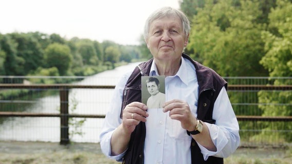 Der Fluchthelfer Hartmut Richter steht auf einer Brücke und hält ein Foto in den Händen. © jump medien TV GmbH 