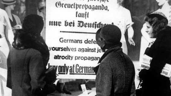Drei deutsche Frauen lesen im April 1933 ein Plakat am Schaufenster eines Geschäfts, das zum Boykott von jüdischen Geschäften aufruft: "Deutsche, verteidigt Euch gegen die jüdische Greuelpropaganda, kauft nur bei Deutschen!". Drei deutsche Frauen lesen im April 1933 ein Plakat am Schaufenster eines Geschäfts, das zum Boykott von jüdischen Geschäften aufruft: "Deutsche, verteidigt Euch gegen die jüdische Greuelpropaganda, kauft nur bei Deutschen!". © picture-alliance / dpa | UPI
