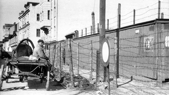Ein Mann sitzt 1942 im Rigaer Judenghetto auf einem Karrenwagen vor einem Stacheldrahtzaun. (Bundesarchiv, Bild 183-N1212-325 / Donath, Herbert / CC-BY-SA 3.0) © Creative Commons License / CC-BY-SA 3.0 Foto: Otto Donath