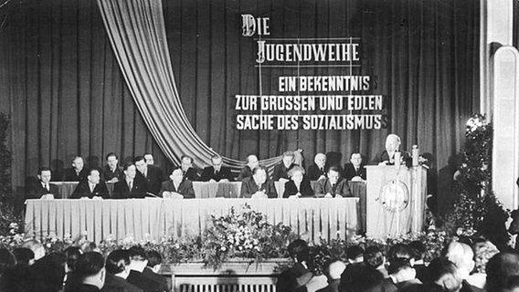 1958 spricht Walter Ulbricht (Podium rechts) in Gera aus Anlaß des Bezirkstreffens mit Teilnehmern an der Jugendweihe in Gera. © Bundesarchiv 