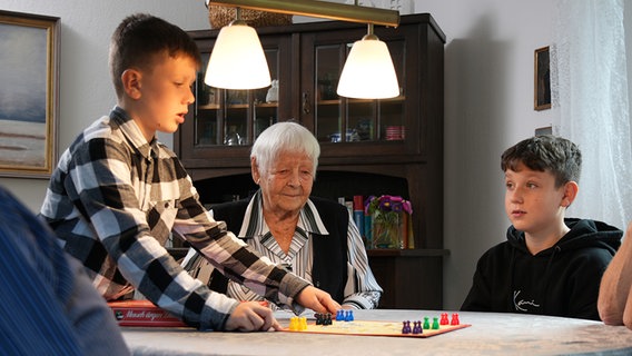Ingeborg Illing aus Salzgitter mit zwei ihrer Enkelkinder beim Spielen am Wohnzimmertisch. © NDR 