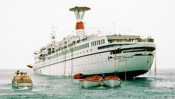 Das havarierte TS "Maxim Gorkiy" treibt im Juni 1989 im Nordmeer, im Vordergrund sind einige leere Rettungsboote zu sehen. © dpa - Report Foto: Arndt