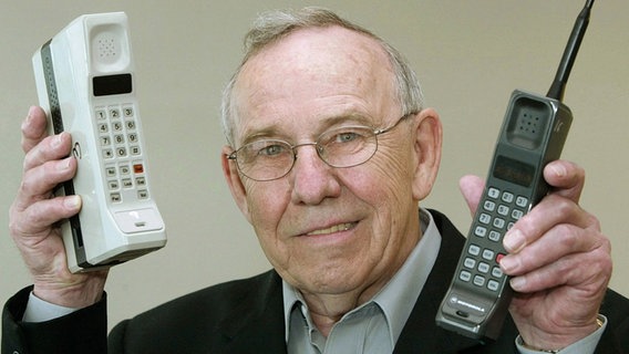 Rudy Krolopp, der Designer des ersten Handys, hält ein Motorola International 3200 (rechts) in die Kamera. Links ein DynaTAC 8000X. © picture alliance/AP Images Foto: CHRISTOF STACHE