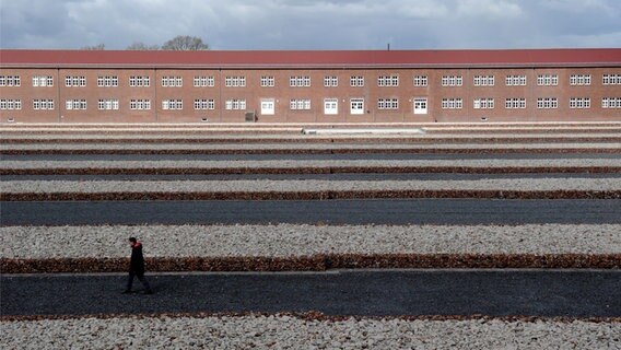 Ein Mann geht in der KZ-Gedenkstätte Neuengamme an mit Steinen gefüllten Gabionen vorbei. © picture alliance / Angelika Warmuth/dpa Foto: Angelika Warmuth