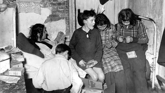 Eine Mutter und ihre vier Kinder auf dem Bett in einer engen Wohnung in Hamburg 1946. © dpa - Report 