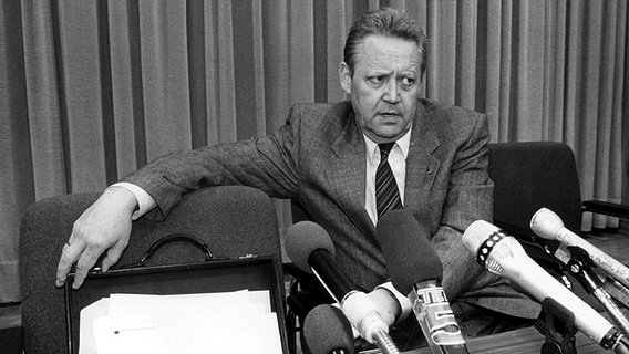 Günter Schabowski sitzt bei einer Pressekonferenz am 9. November 1989 an einem Tisch hinter zahlreichen Mikrofonen. © picture alliance / dpa 