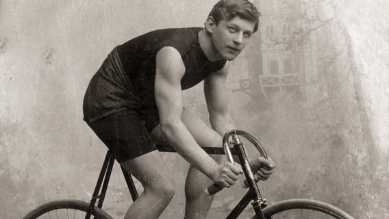 Der Radfahrer Willy Arend posiert in einem Fotostudio auf seinem Rennrad. © RV Endspurt Hamburg Foto: Robert Wiesenhavern