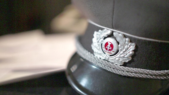 Eine Mütze der Deutschen Demokratischen Republik liegt auf einem Tisch. © NDR 