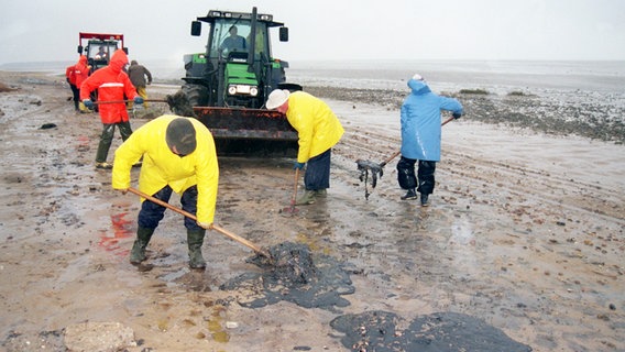 Mit Schaufeln beseitigen Einheimische im November 1998 auf der Nordseeinsel Föhr Ölflecken vom Strand. © picture-alliance / dpa Foto: Wulf Pfeiffer