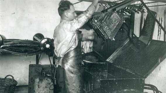 Aus der Anfangszeit (circa 1929 bis 1934) stammt auch diese Aufnahme: Ein Arbeiter ist im Wandsbeker Werk mit der Oberflächenbehandlung von Metallteilen befasst. Die Schürze scheint sein einziger Schutz zu sein. © Daimler 