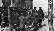 Zwangsarbeiter im Warschauer Ghetto hinter einem Stacheldraht-Zaun Anfang 1941. © picture-alliance / akg-images | akg-images 