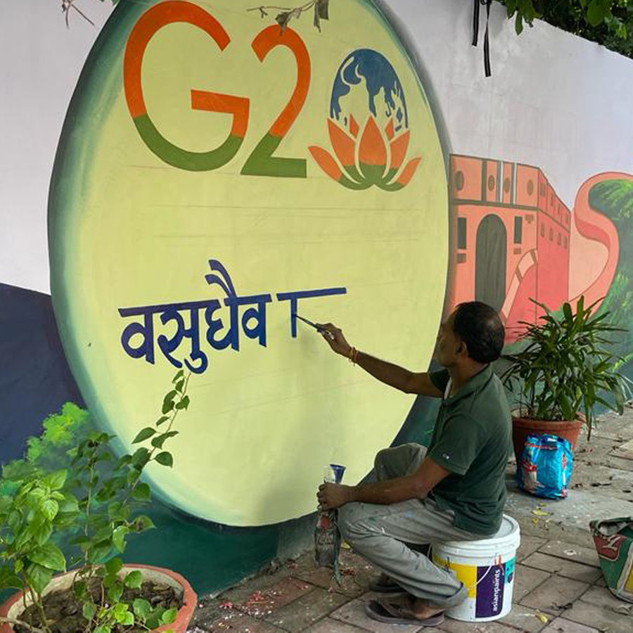 G20 Gipfel in Neu Delhi, ein Mann malt das G20-Logo mit Lotusblüte auf eine weiße Mauer © NDR/Peter Hornung Foto: Peter Hornung