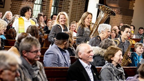 Eine Pfarrerin kommt mit einer Brass Band zum Gottesdienst. © picture alliance/dpa | Fabian Sommer Foto: Fabian Sommer