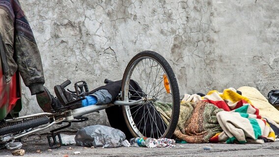 Ein Obdachloser liegt nicht direkt sichtbar inmitten von Habseligkeiten. © Colourbox Foto: -