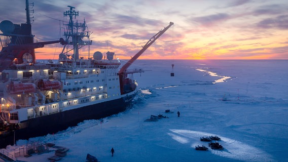 Ein Schiff mit Kran im Eis bei tiefem Sonnenstand. © picture alliance Foto: Stefan Hendricks