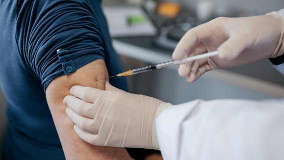 Ein Arzt setzt eine Spritze in den Arm eines Mannes. © Photocase Foto: David Pereiras