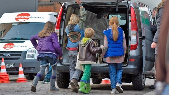 Kinder öffnen die Heckklappe von einem Lieferwagen © NDR Foto: Claudia Timmann
