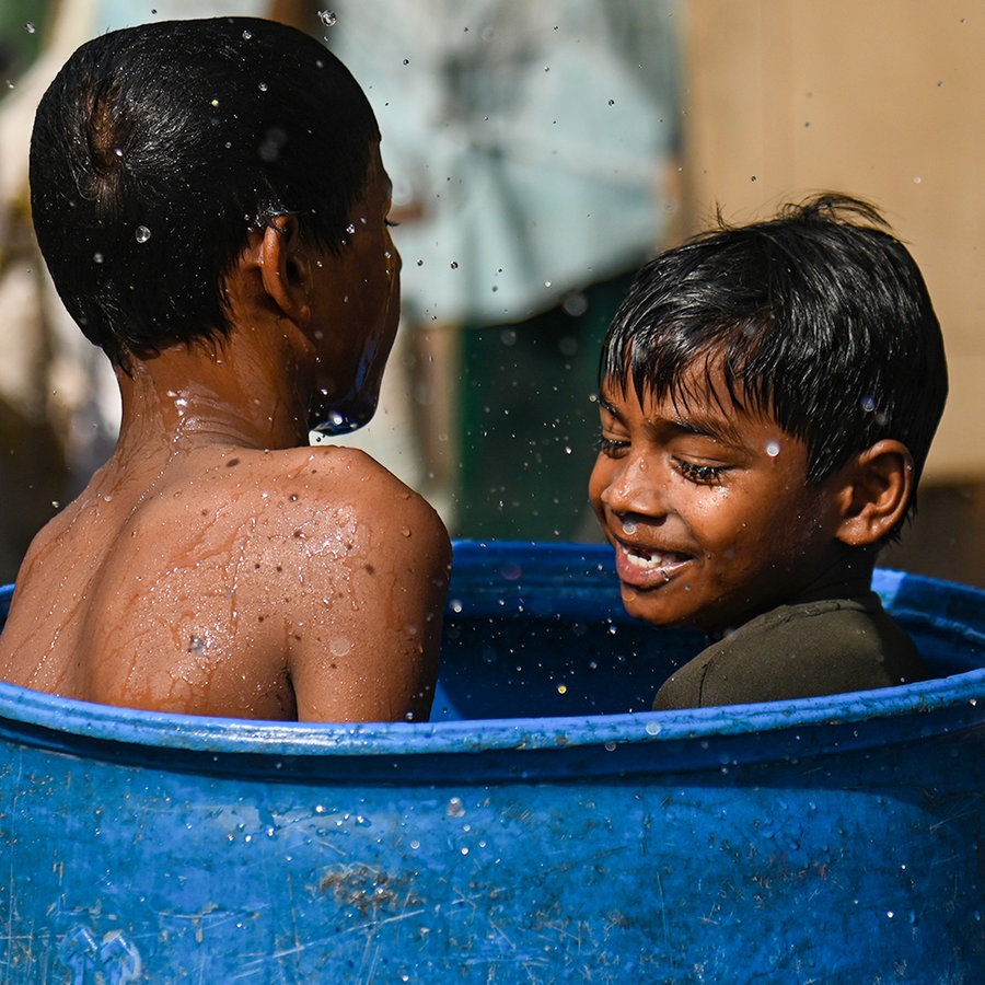 Zwei kleine Jungen in Indien erfrischen sich in einer Wassertonne © picture alliance Foto: Kabir Jhangiani
