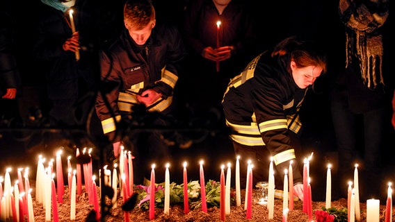 Personen zünden Kerzen zum Gedenken an die Opfer des Messerangriffs an. © picture alliancedpa Foto: Axel Heimken