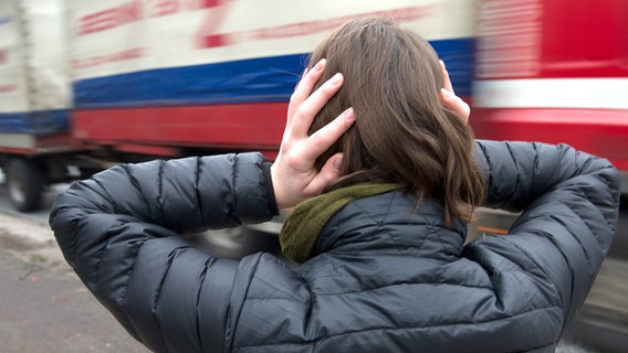 Eine Frau hält sich vor einem herannahenden Lastwagen die Ohren zu. © picture alliance / dpa Foto: Axel Heimken