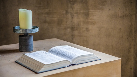 Ein Holztisch mit Kerze und aufgeschlagener Bibel. © Christine Raczka 