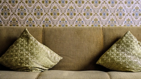 Ein Sofa in Stil der 70er vor einer gemusterten Tapete. © photocase Foto: macingosh