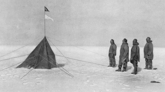 Roald Amundsen und drei weitere Männer stehen vor einer Flagge am Südpol. © picture alliance/Mary Evans Picture Library 
