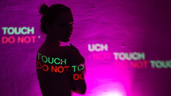 Die Aufschrift "Do Not Touch" wird auf den Körper einer jungen Frau projiziert. © picture alliance / Zoonar 