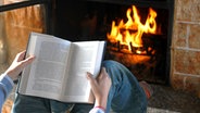 Eine Person liest ein Buch vor dem Kaminfeuer © Fotolia Foto: Dario Airoldi