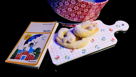 Zuckerbrezeln neben einer Keksdose und einem Buch ("Madita) - Folge 47 von eat.READ.sleep © NDR Foto: Tim Piotraschke