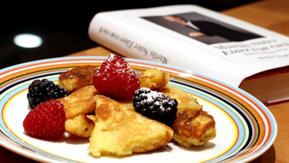 Kaiserschmarrn mit Früchten neben einem Buch von Martin Suter - Folge 57 von eat.READ.sleep © NDR Foto: Claudius Seidl