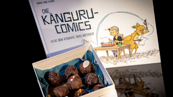 Schnapspralinen in einer Box neben einem Buch von "Känguru Comics" - Folgenfoto von eat.READ.sleep. © NDR 