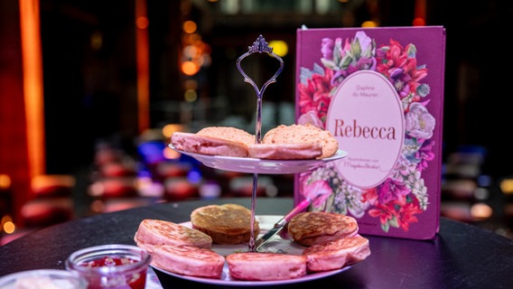 Zwei Crumpets auf einer Etagere neben dem Buch "Rebecca" - Folgenfoto von eat.READ.sleep © NDR 