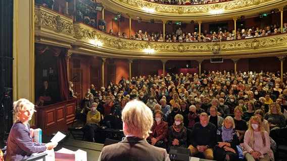 Die Hosts Katharina Mahrenholtz (r.) und Jan Ehlert sitzen im Deutschen Theater Göttingen auf der Bühne, der Saal ist voll besetzt © NDR Foto: Christoph Mischke